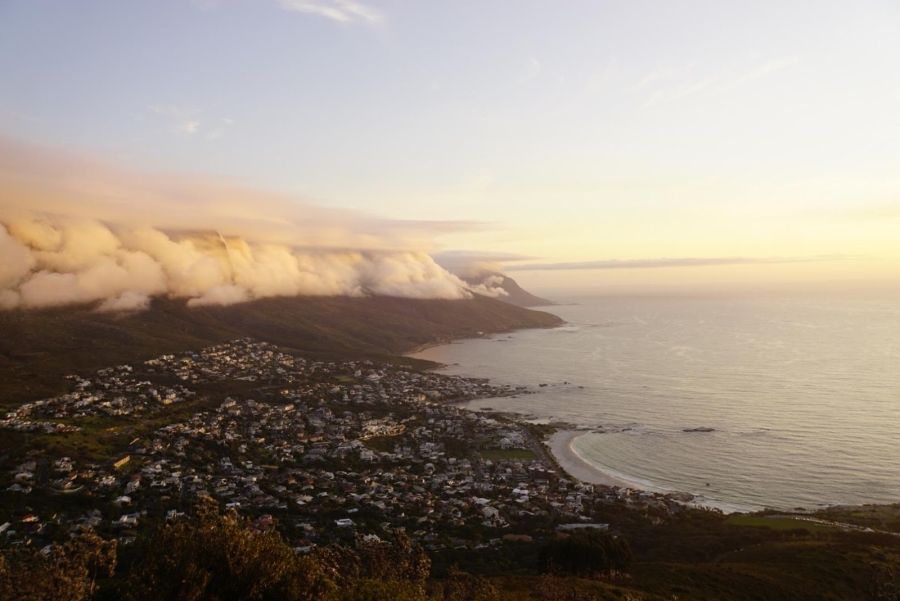 Sonnenuntergang mit Blick auf den Tafelberg, eingehüllt in Wolken, am Fuße des Berges liegt Kapstadt